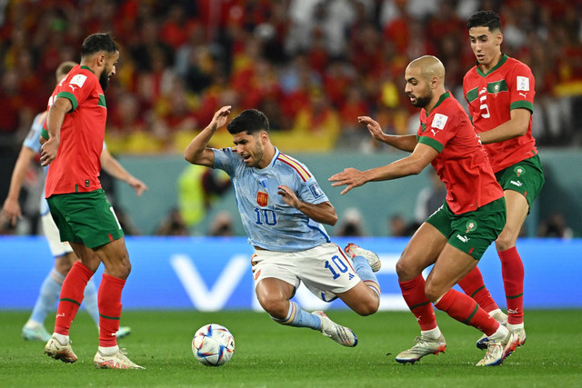 Pemain Timnas Spanyol Marco Asensio dihadang pemain Timnas Maroko Nayef Aguerd pada pertandingan 16 besar Piala Dunia 2022 Qatar di Education City Stadium, Al Rayyan, Qatar. Foto: Dylan Martinez/REUTERS