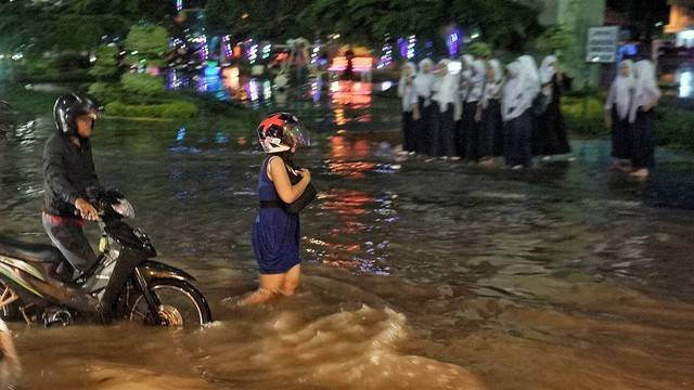 Pengendara motor yang terjebak banjir akibat meluapnya kolam retensi di kawasan simpang polda pasca hujan deras di Palembang, Foto: abp/Urban Id