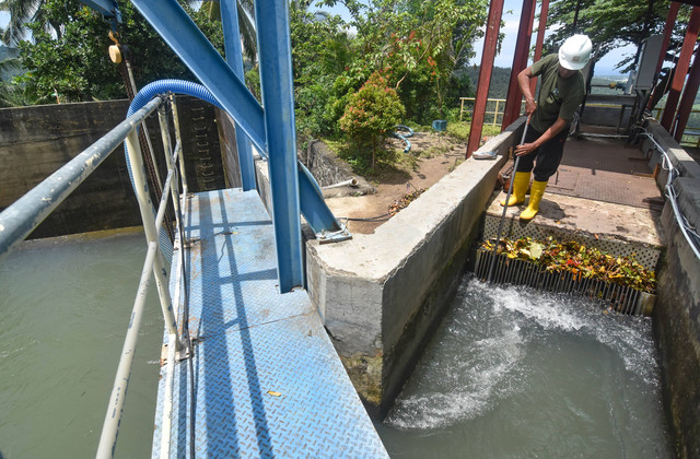 Seorang pekerja membersihkan sampah yang tersangkut di kolam penampungan air Pembangkit Listrik Tenaga Mini Hidro (PLTMH) Segara di Desa Bentek, Kecamatan Gangga, Lombok Utara, NTB, Rabu (14/12/2022). Foto: Ahmad Subaidi/ANTARA FOTO