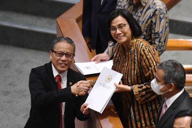 Menteri Keuangan Sri Mulyani Indrawati menerima berkas hasil rapat dan pandangan mini fraksi dari Ketua Panja pembahasan Rancangan Undang-Undang (RUU) tentang Pengembangan dan Penguatan Sektor Keuangan (PPSK) Dolfie OFP (kiri) saat rapat paripurna. Foto: Hafidz Mubarak A/Antara Foto