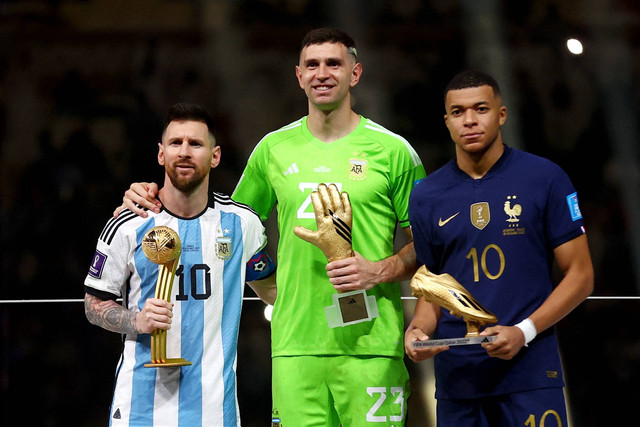 Pemenang Bola Emas Lionel Messi dari Argentina, pemenang Sarung Tangan Emas Emiliano Martinez dari Argentina, dan pemenang Sepatu Emas Kylian Mbappe dari Prancis berpose dengan trofi di Stadion Lusail, Lusail, Qatar, Minggu (18/12/2022). Foto: Carl Recine/REUTERS