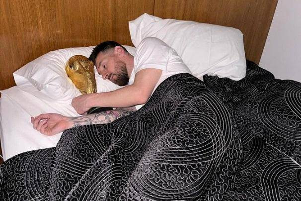 Pemain Argentina Lionel Messi terbaring di tempat tidur dengan trofi Piala Dunia FIFA, di lokasi yang tidak diketahui, dalam media sosial dan dirilis pada 20 Desember 2022. Foto: Instagram/leomessi/via REUTERS 