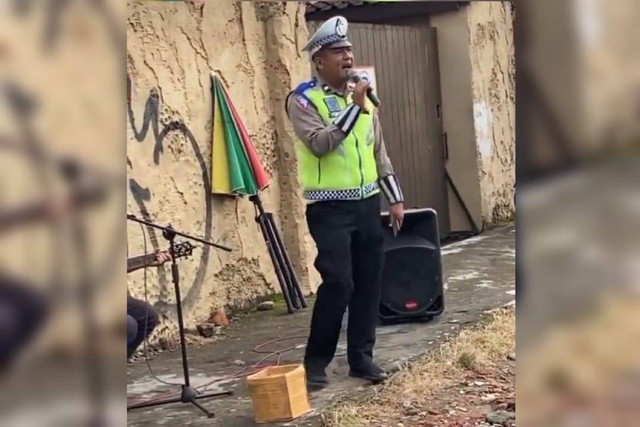 Seorang polisi yang karaoke sambil atur lalu lintas bareng pengamen di Jogja. Foto: istimewa