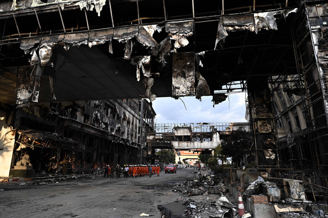 Sebuah tim penyelamat berjalan melalui bagian kasino hotel Grand Diamond City yang terbakar setelah kebakaran besar di kompleks tersebut, di Poipet di provinsi Banteay Meanchey pada 30 Desember 2022.  Foto: Lillian Suwanrumpha/AFP