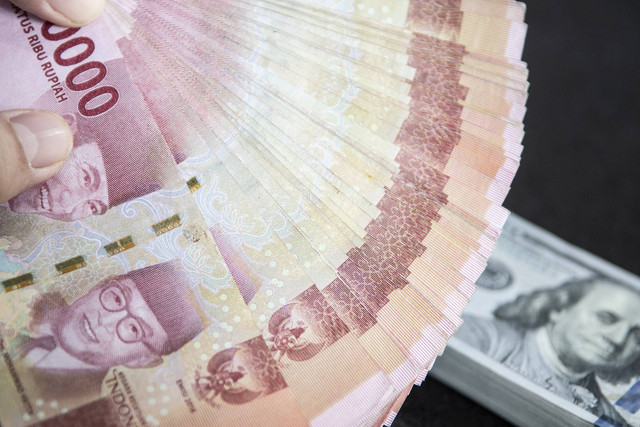 Petugas menunjukan uang pecahan rupiah dan dolar AS di gerai penukaran mata uang asing VIP (Valuta Inti Prima) Money Changer, Jakarta, Selasa (3/1/2023). Foto: Muhammad Adimaja/Antara Foto