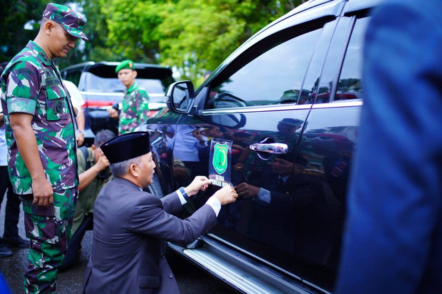 Pj Bupati Muba Apriyadi saat menempel stiker di mobil dinas. (ist)