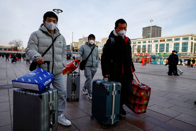 Orang-orang berjalan dengan barang-barangnya di jalan layang ke Stasiun Kereta Api Beijing, menjelang Tahun Baru Imlek, di Beijing, China, Sabtu (7/1/2023). Foto: Tingshu Wang/REUTERS