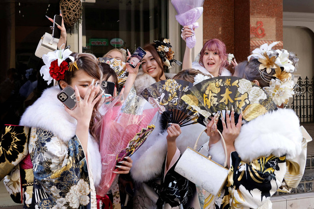 Wanita muda berkimono berpose untuk seorang fotografer di dekat sebuah tempat dalam upacara perayaan Hari Kedewasaan di Yokohama, Jepang, Senin (9/1/2023). Foto: Kim Kyung-Hoon/REUTERS