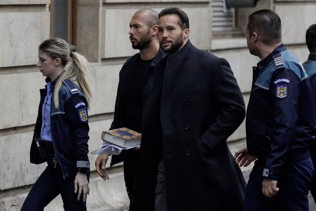 Andrew Tate tampak membawa Al-Quran. Dia bersama saudaranya Tristan dikawal oleh petugas polisi di luar markas Pengadilan Banding Bucharest, di Bucharest, Rumania, 10 Januari 2023. Foto: Inquam Photos/Octav Ganea via REUTERS