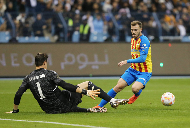 Toni Lato dari Valencia duel dengan Thibaut Courtois dari Real Madrid saat pertandingan di Stadion King Fahd, Riyadh, Arab Saudi. Foto: Ahmed Yosri/Reuters