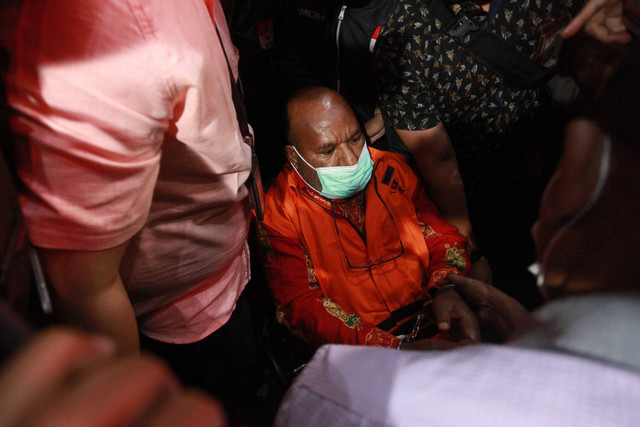 Tersangka Gubernur Papua Lukas Enembe (tengah) yang duduk di kursi roda dikawal petugas menuju mobil tahanan usai menjalani pemeriksaan di Gedung Merah Putih KPK, Jakarta, Kamis (12/1/2023). Foto: Reno Esnir/Antara Foto