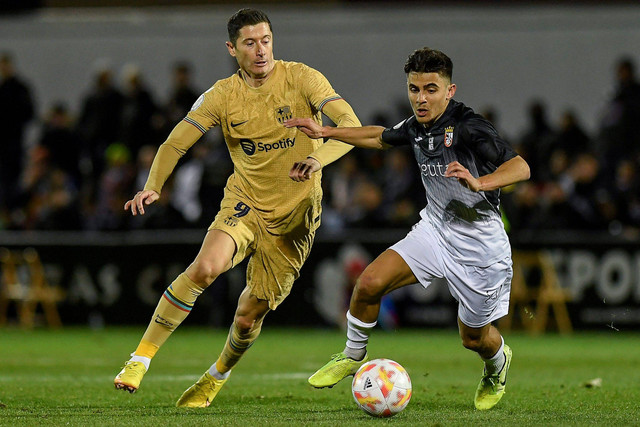 Pemain FC Barcelona Robert Lewandowski berebut bola dengan pemain AD Ceuta pada pertandingan 16 besar Copa del Rey di Stadion Alfonso Murube, Ceuta, Spanyol, Kamis (19/1/2023). Foto: JORGE GUERRERO / AFP