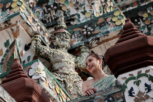 Wisatawan yang mengenakan kostum tradisional Thailand mengunjungi kuil Wat Arun di Bangkok, Thailand. Foto: Chalinee Thirasupa/REUTERS