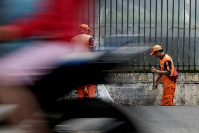 Pekerja Petugas Pelayanan Prasarana dan Sarana Umum (PPSU) tampak sedang membersihkan got. Foto: Fanny Kusumawardhani/kumparan