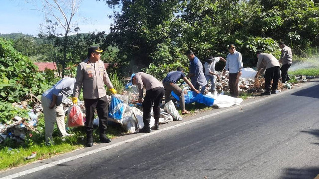 Kapolres Kota Subulussalam AKBP Yhogi Hadi Setiawan menyempatkan diri untuk memungut sampah yang menumpuk di sisi kiri badan jalan lintas nasional Tapaktuan-Subulussalam. Foto: Yudi Ansyah/acehkini