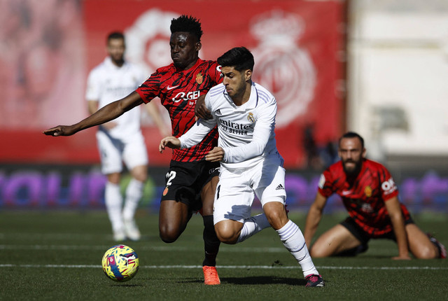 Iddrisu Baba (kiri) berduel dengan Marco Asensio di laga Real Mallorca vs Real Madrid dalam laga lanjutan Liga Spanyol 2022/23 di Stadion Iberostar pada 5 Februari 2023. Foto: REUTERS/Juan Medina