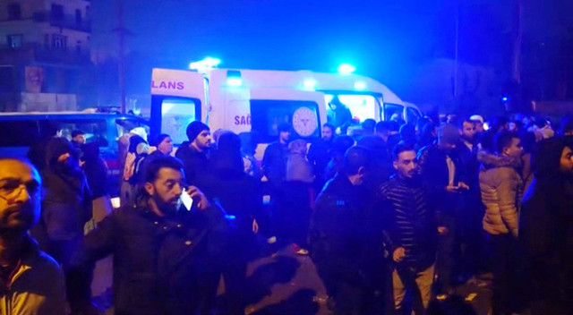 Warga berdiri di dekat ambulans saat tim penyelamat bekerja di tengah puing-puing bangunan yang runtuh setelah gempa bumi di Diyarbakir, Turki, Senin (6/2/2023).  Foto: REUTERS