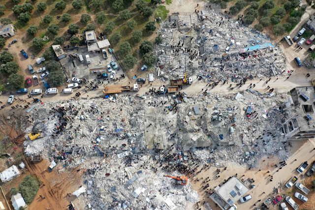 Sejumlah penduduk mencari korban yang tertimpa puing-puing bangunan yang runtuh setelah gempa bumi di desa Besnia dekat Twon Harim, di provinsi Idlib Suriah, pada Senin (6/2/2023). Foto: Omar Haj Kadour/AFP