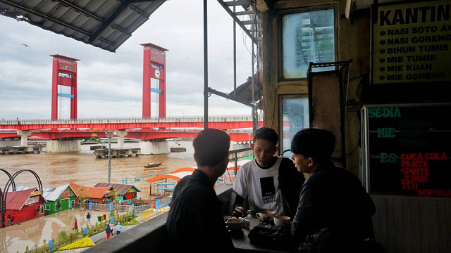 Para pengujung kedai yang bersantai menikmati kopi di Agam Pisan kedai kopi unik berlatar lanskap Sungai Musi Palembang, Senin (27/2) Foto: abp/Urban Id