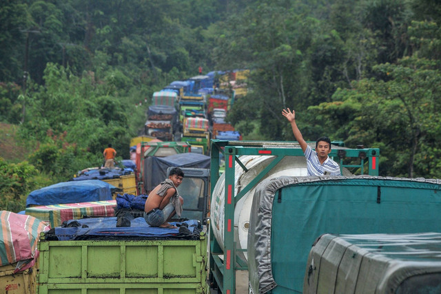 Sopir berdiri di atas truk saat terjadi antrean kendaraan yang didominasi truk bermuatan batu bara di Jalan Lintas Sarolangun-Muara Tembesi, Batanghari, Jambi, Rabu (1/3/2023). Foto: Wahdi Septiawan/ANTARA FOTO