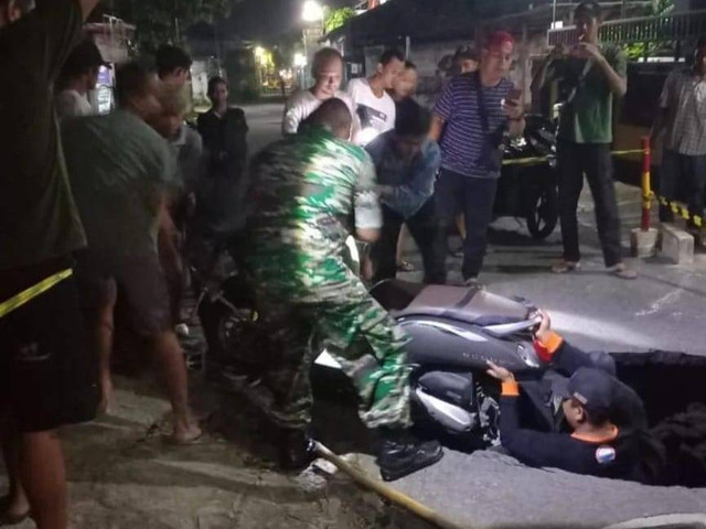 Petugas mengevakuasi motor yang terperosok ke dalam lubang di jalanan Jogja. Foto: Twitter/@merapi_uncover