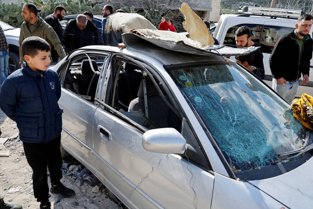 Orang-orang melihat mobil yang rusak setelah operasi mematikan Israel, dekat Jenin, di Tepi Barat yang diduduki Israel, Kamis (9/3/2023). Foto: Raneen Sawafta/REUTERS 