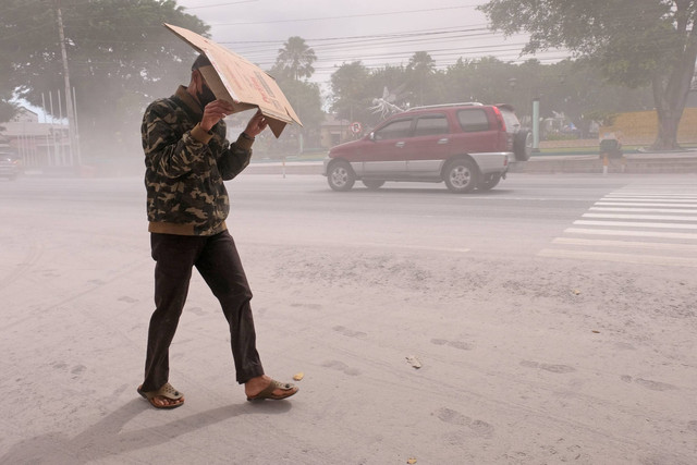 Warga melindungi diri dari abu menggunakan kardus saat melintas di jalan utama kota Magelang yang diselimuti abu vulkanis gunung Merapi di Magelang, Jawa Tengah, Sabtu (11/3/2023). Foto: Anis Efizudin/ANTARA FOTO
