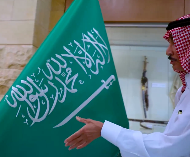 Kaligrafer Saleh Al-Mansouf dan bendera Arab Saudi.
Foto: Twitter/@Darahfoundation
