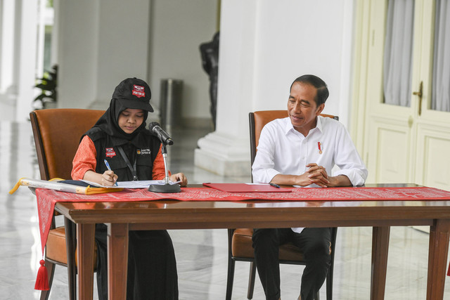 Presiden Joko Widodo (kanan) menyaksikan petugas pemutakhiran data pemilih (Pantarlih) mencocokan dokumen kependudukannya saat proses pencocokan dan penelitian (Coklit) data pemilih untuk Pemilu 2024 di Istana Merdeka, Jakarta, Selasa (14/2/2023). Foto: Hafidz Mubarak A/Antara Foto