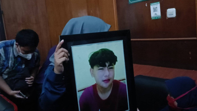 Salah satu keluarga korban membawa foto anaknya yang meninggal akibat tragedi Kanjuruhan di persidangan putusan tiga terdakwa dari anggota Polri di Pengadilan Negeri (PN) Surabaya, Kamis (16/3/2023). Foto: Farusma Okta Verdian/kumparan