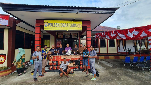 Sopir (jongkok) bersama barang bukti minuman keras jenis bir diamankan di Mapolsek Oba Utara, Kota Tidore Kepulauan, Maluku Utara. Dok: Polsek Oba Utara