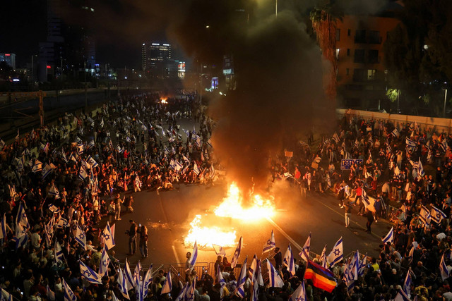 Orang-orang melakukan demonstrasi setelah Perdana Menteri Israel Benjamin Netanyahu memecat menteri pertahanan dan pemerintah koalisi nasionalisnya melanjutkan pemeriksaan yudisialnya, di Yerusalem, Senin (27/3/2023). Foto: Ammar Awad/REUTERS