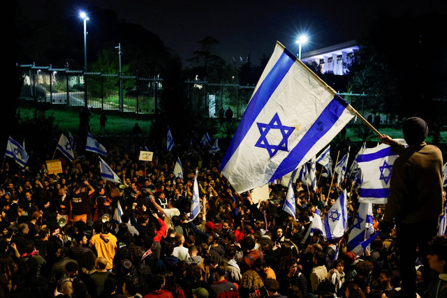 Orang-orang melakukan demonstrasi setelah Perdana Menteri Israel Benjamin Netanyahu memecat menteri pertahanan dan pemerintah koalisi nasionalisnya melanjutkan pemeriksaan yudisialnya, di Yerusalem, Senin (27/3/2023). Foto: Ammar Awad/REUTERS