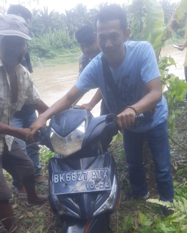 Warga membantu mengevakuasi sepeda motor Poniman dari dalam sungai ke daratan. (Foto: Humas Polres Langkat)