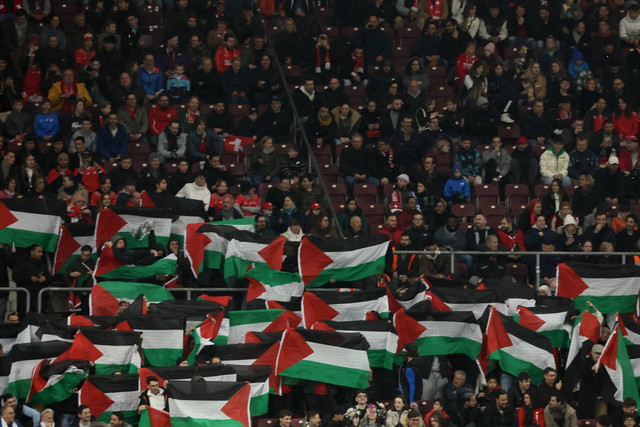 Fans mengibarkan bendera Palestina selama pertandingan Swiss vs Israel pada Kualifikasi UEFA Euro 2024 di Stade de Geneve, Lancy, Swiss, Selas (28/3/2023). Foto: Denis Balibouse/REUTERS