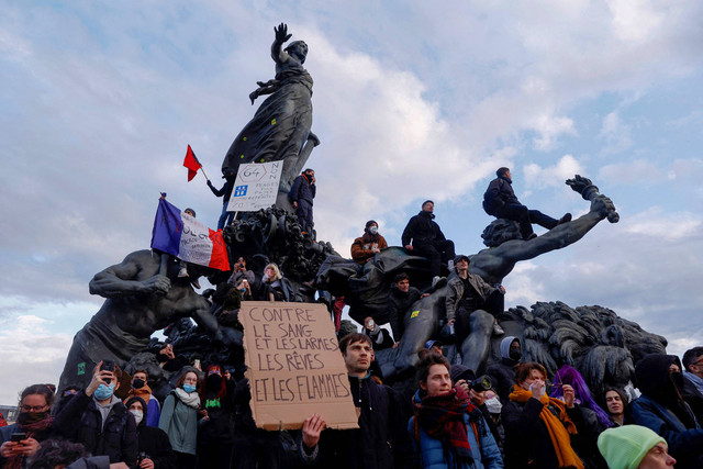 Para pengunjuk rasa memegang bendera nasional Prancis saat mereka berdiri di atas patung Place de la Nation selama unjuk rasa hari ke 10 pemogokan nasional dan protes terhadap reformasi pensiun pemerintah Prancis di Paris, Prancis, 28 Maret 2023. Foto: Gonzalo Fuentes/Reuters