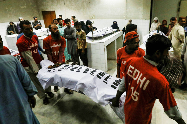 Petugas penyelamat memindahkan jenazah seorang korban, yang tewas akibat terinjak-injak di pusat distribusi bansos di Karachi, Pakistan 31 Maret 2023.. Foto: Akhtar Soomro/Reuters