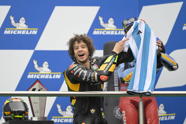 Marco Bezzecchi pamer jersi Argentina bertanda tangan Lionel Messi di podium MotoGP Argentina 2023 di Autodromo Termas de Rio Hondo pada 3 April 2023. Foto: JUAN MABROMATA / AFP