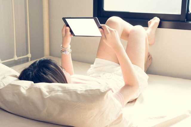 Ilustrasi bermain gadget sambil tiduran. Foto: Just2shutter/Shutterstock