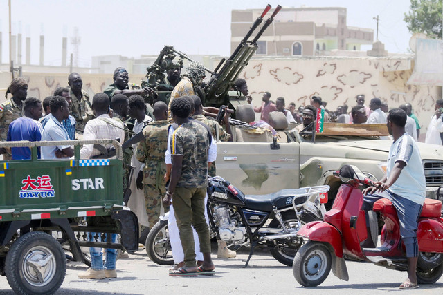 Warga berkumpul dengan tentara yang setia kepada panglima militer Abdel Fattah al-Burhan, di kota Laut Merah Port Sudan pada 16 April 2023. Foto: AFP