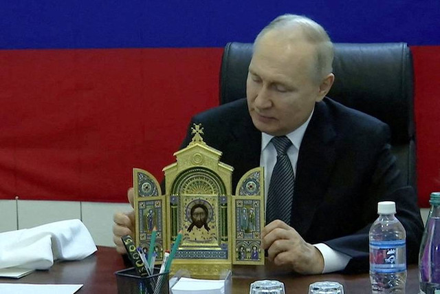 Presiden Rusia Vladimir Putin mempersembahkan ikon Ortodoks kepada komandan militer saat ia mengunjungi markas besar kelompok tentara "Dnieper" di Wilayah Kherson, Ukraina yang dikuasai Rusia, Selasa (18/4/2023). Foto: Kremlin.ru/Handout via REUTERS