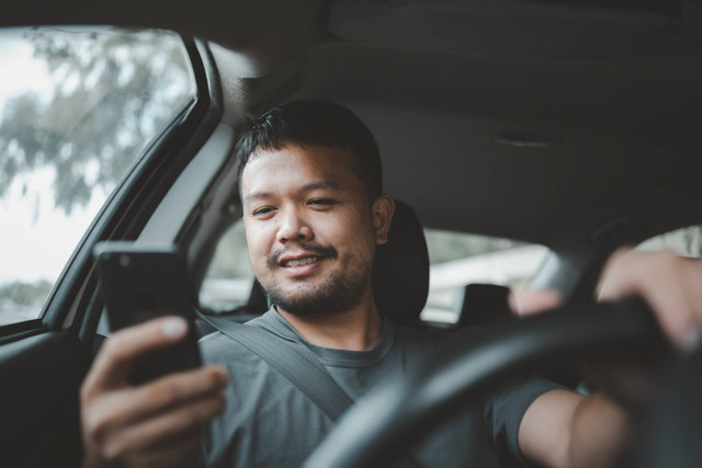 Ilustrasi main handphone saat menyetir mobil. Foto: Shutterstock