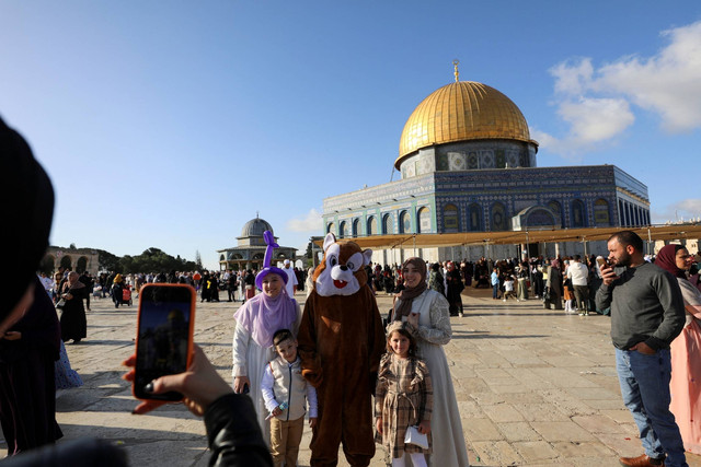 Warga Palestina berfoto bersama usai salat Idul Fitri di kompleks masjid al-Aqsa, di Kota Tua Yerusalem, Jumat (21/4/2023). Foto: Jamal Awad/REUTERS