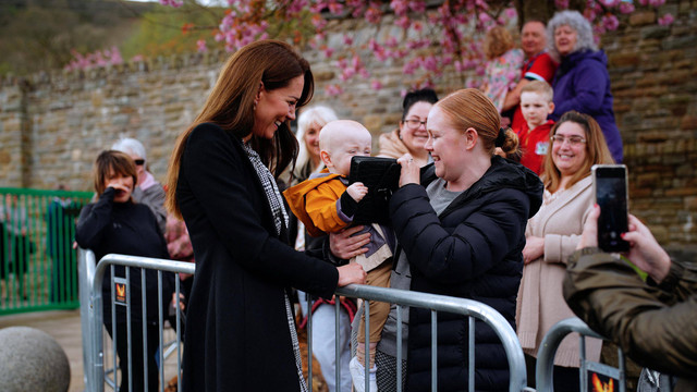 Lucy Williams (kanan), dari Aberfan, menggendong putranya yang berusia satu tahun, Daniel Williams, saat dia mengambil tas tangan Kate Middleton (kiri) di Aberfan, Wales selatan pada tanggal 28 April 2023. Foto: Ben Birchall/AFP