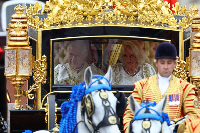 Raja Charles III dan Ratu Camilla melakukan perjalanan dengan Diamond Jubilee State Coach dari Istana Buckingham ke Westminster Abbey untuk upacara penobatan mereka di London, Inggris, Sabtu (6/5/2023). Foto: Hannah McKay/REUTERS