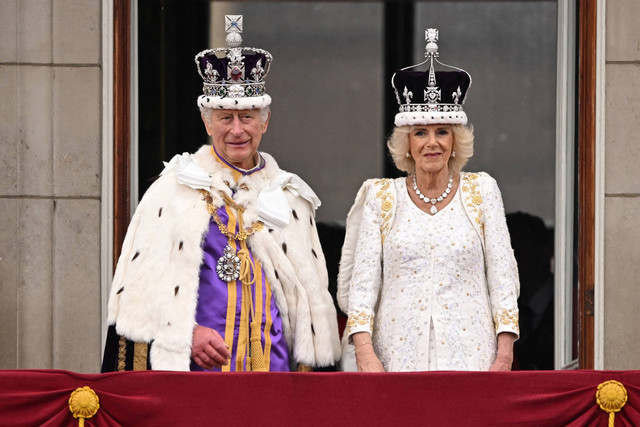 Raja Charles III mengenakan Mahkota negara Kekaisaran, dan Ratu Inggris Camilla mengenakan versi modifikasi dari gelombang Mahkota Ratu Mary berdiri di balkon Istana Buckingham, London, Sabtu (6/5/2023). Foto: Oli Scarff/AFP