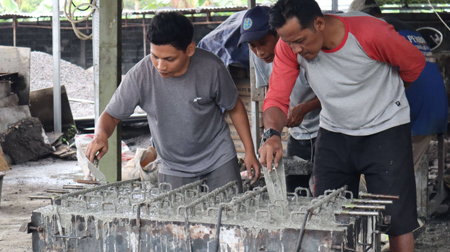 Seorang pekerja limbah sedang meratakan adonan bata daur ulang. Sumber : IMaBs