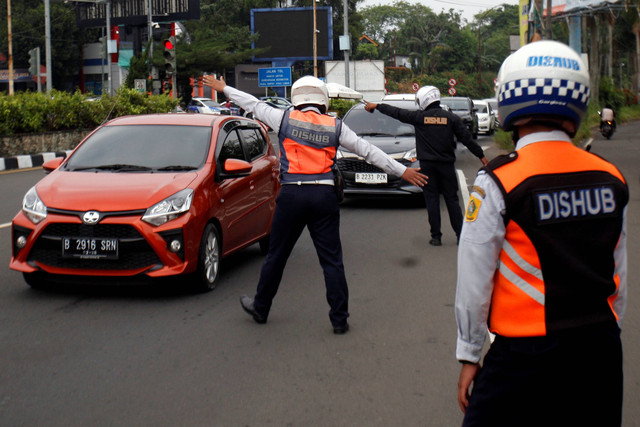 Petugas Sat Lantas Polres Bogor dan petugas Dishub Kabupaten Bogor mengarahkan mobil wisatawan saat penyekatan kendaraan bernomor polisi ganjil genap di jalur wisata Puncak, Gadog, Kabupaten Bogor, Jawa Barat, Kamis (18/5/2023. Foto: Yulius Satria Wijaya/ANTARA FOTO