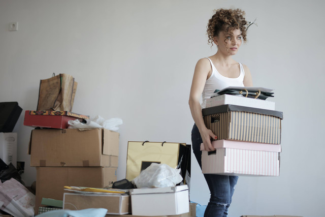 Wanita Yang Berkonsentrasi Membawa Tumpukan Kardus Untuk Relokasi. Foto: Andrea Piacquadio/Pexels