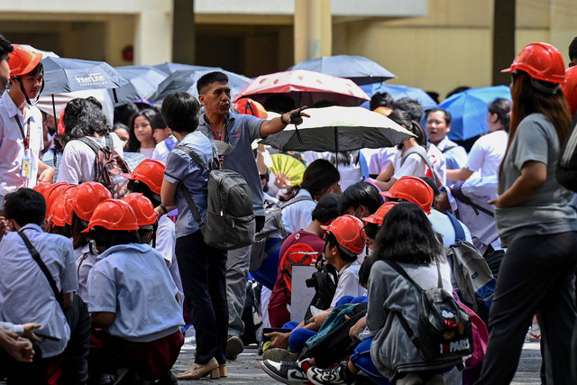 Sejumlah pekerja berkumpul di jalan setelah gempa berkekuatan 6,5 magnitudo di Manila, Filipina, Kamis (15/6/2023). Foto: Jam Sta Rosa/AFP